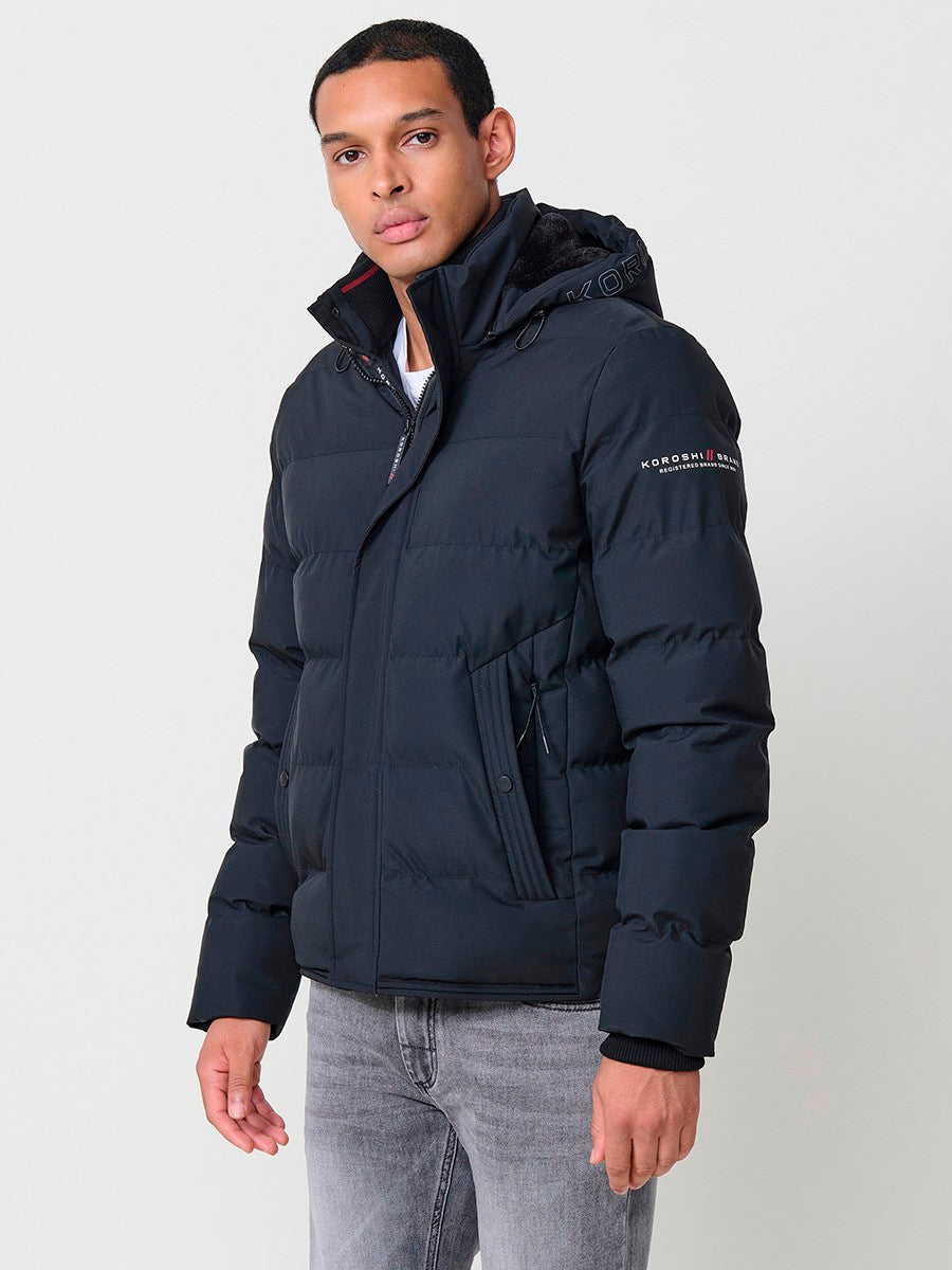 KORÖSHI. Cazadora acolchada antracita de hombre con cuello alto, capucha, bolsillos y cierre delantero de cremallera.