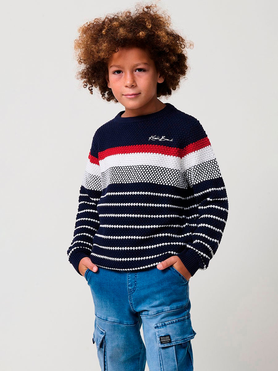 KORÖSHI. Jersey de niño en punto de algodón color navy con rayas crudo y rojas, cuello redondo y puños acanalados.